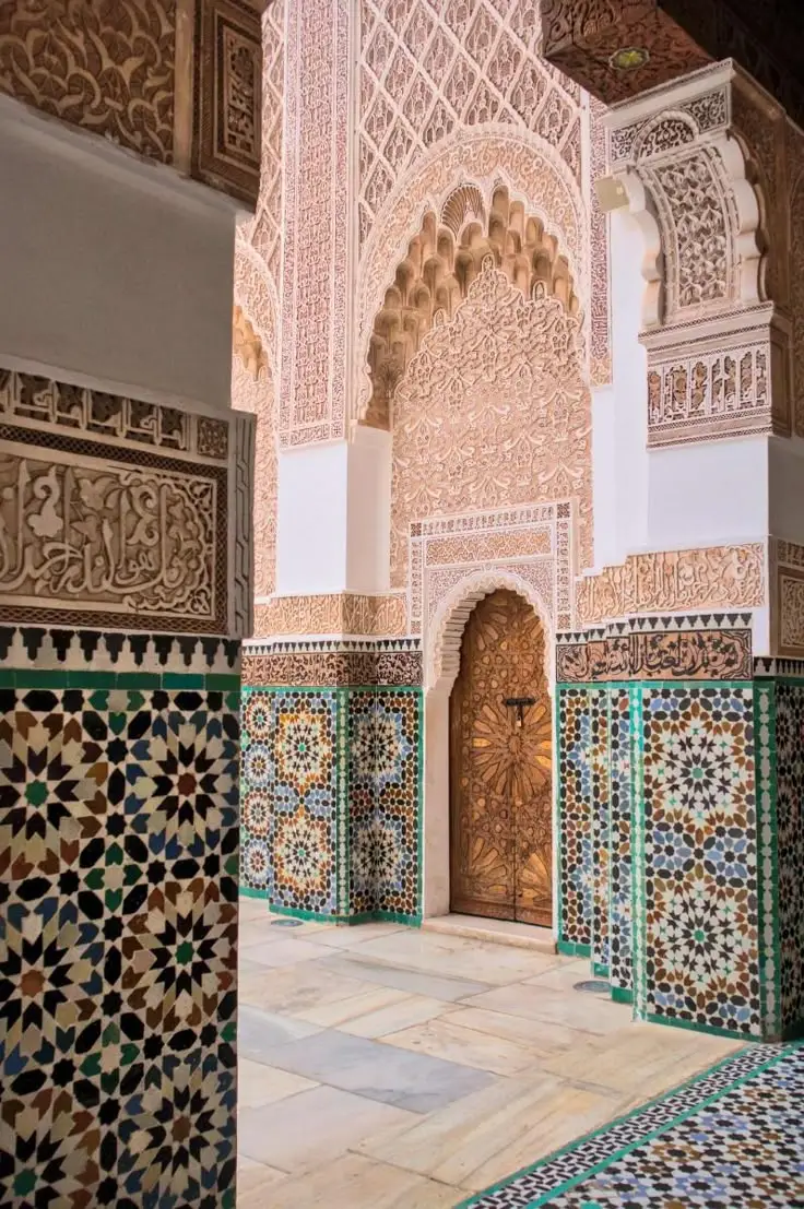 Detailed view of Marrakech architecture featuring red walls, geometric patterns, and elegant arches in a traditional Moroccan riad.